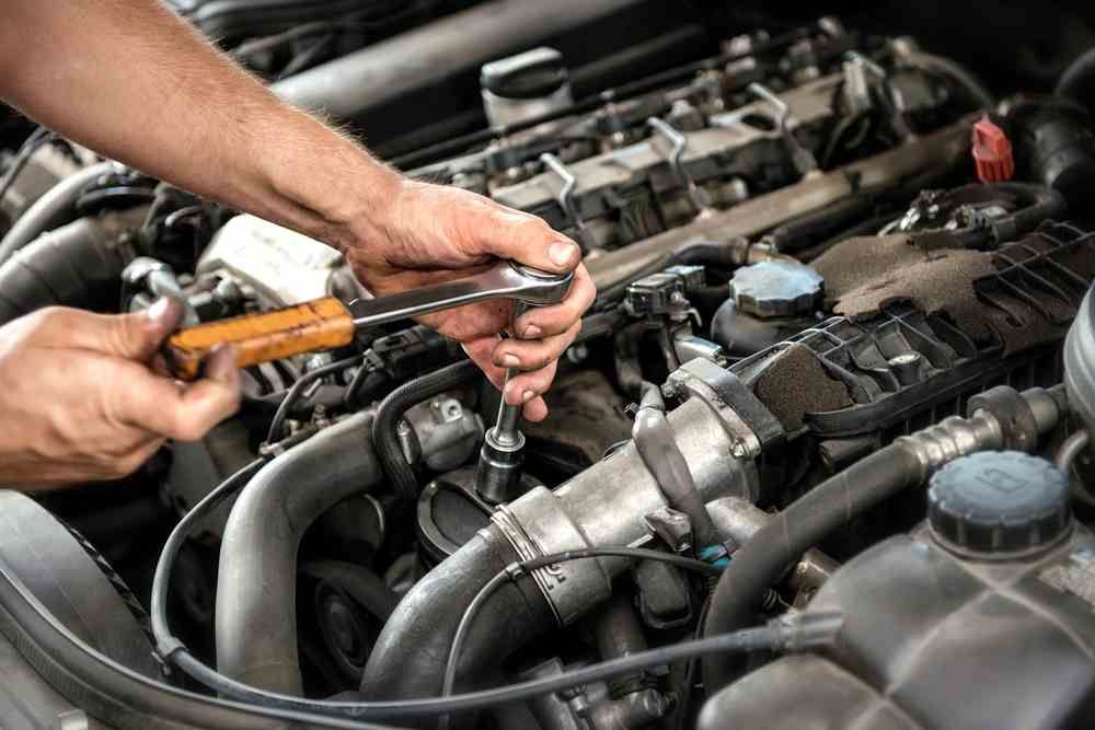 A Man is Working on a Car Engine With a Wrench — Innisfail Pro Motors In Tablelands, QLD