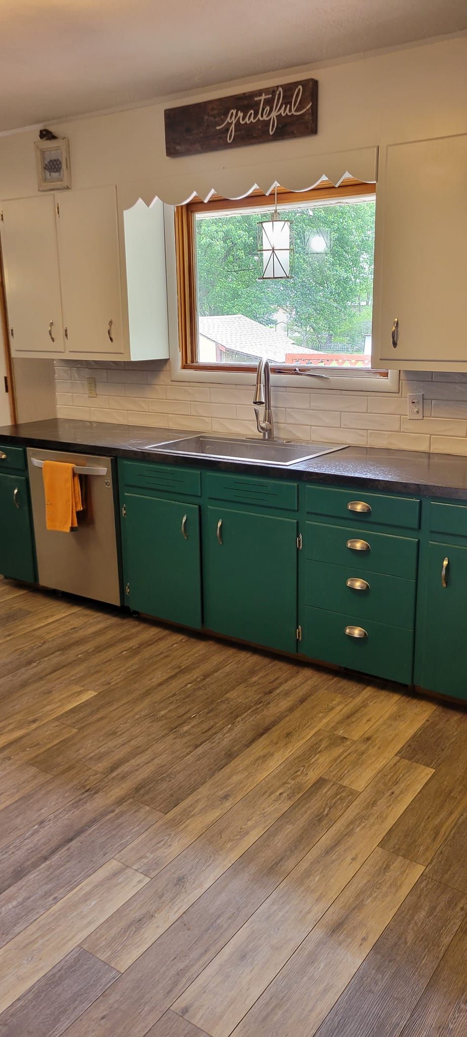Kitchen with green lower cabinets, white upper cabinets, and a window.