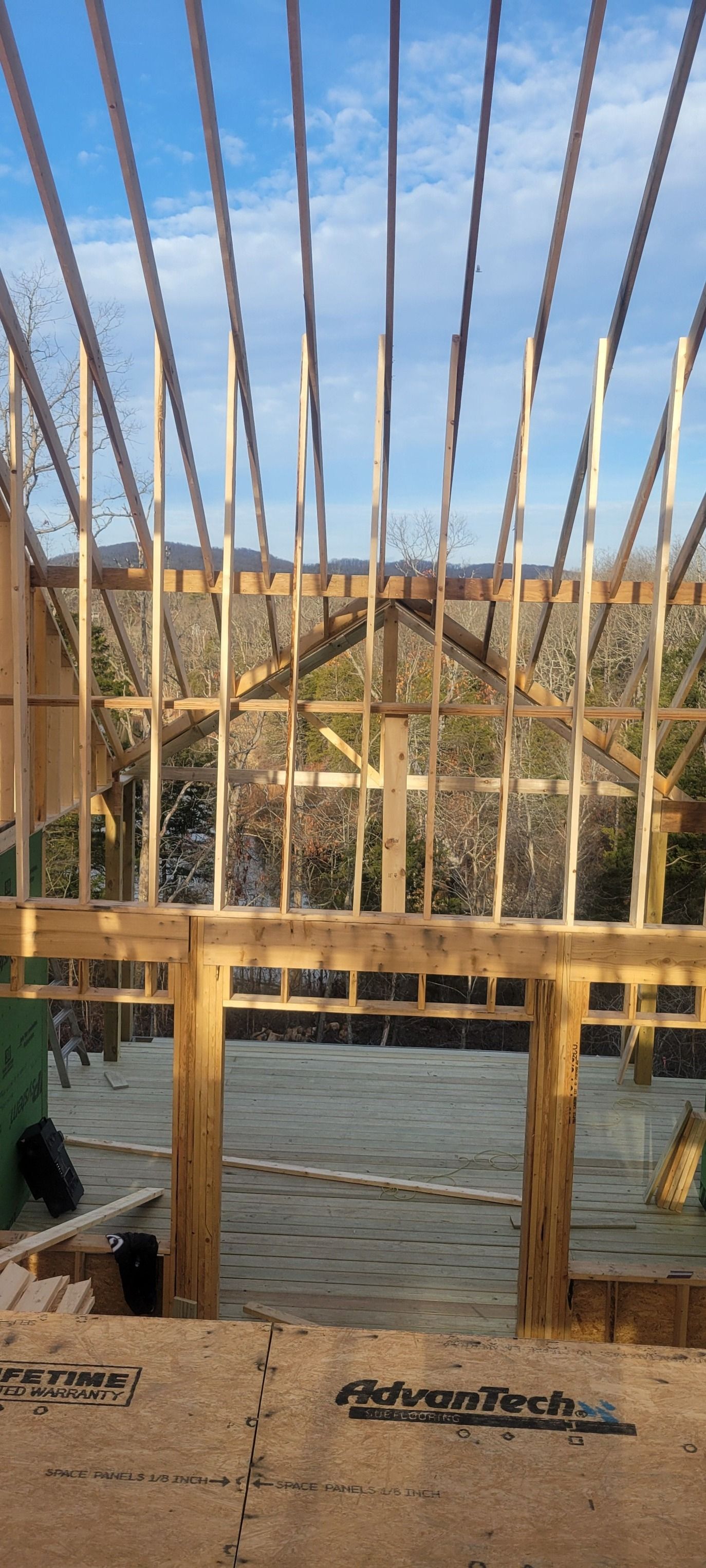 Wooden frame construction against a blue sky, framing a view of trees.
