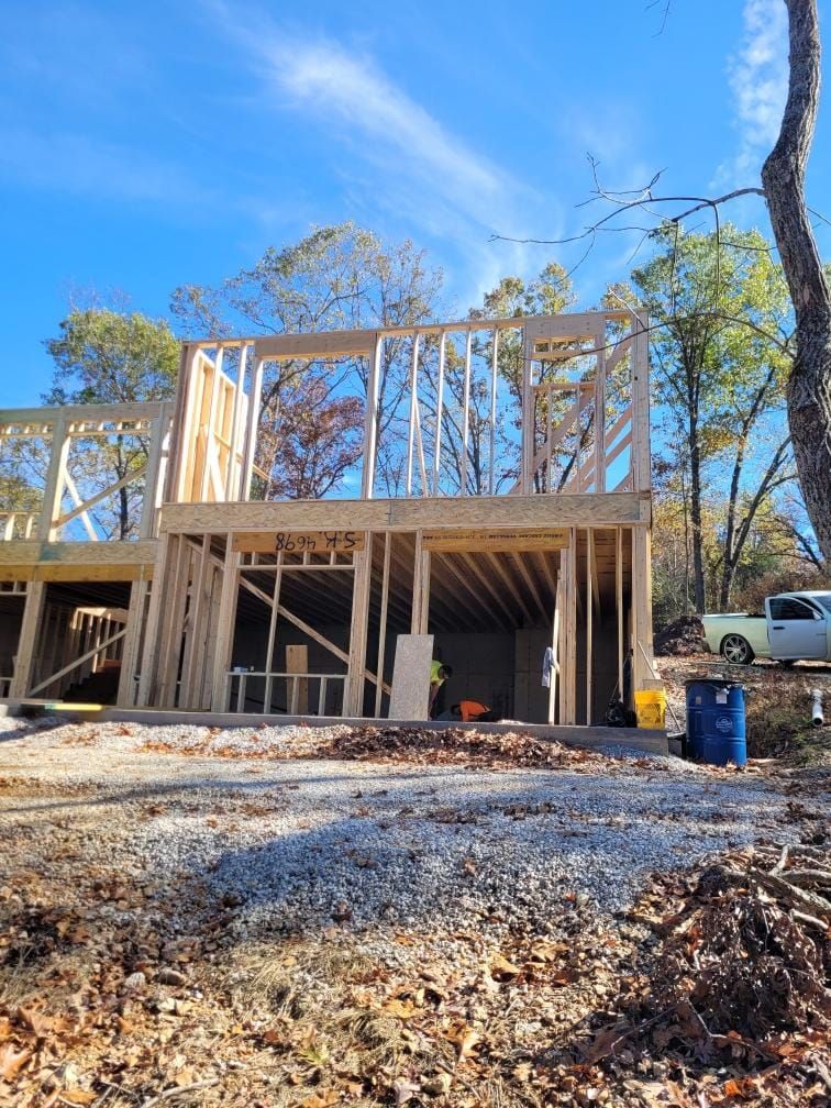 Wooden frame of a house under construction; clear blue sky; construction debris.