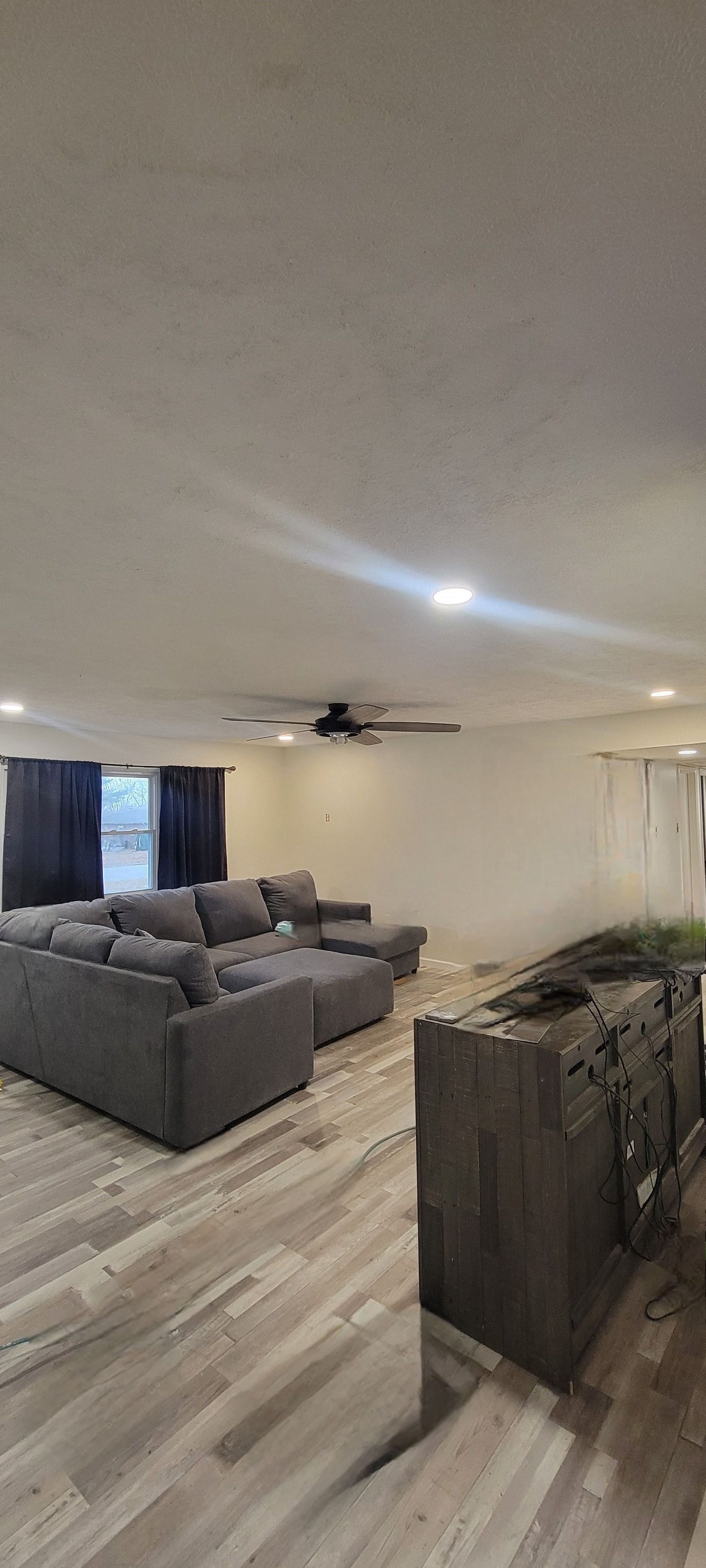Living room with gray sectional sofa, hardwood floor, and a dark TV stand.