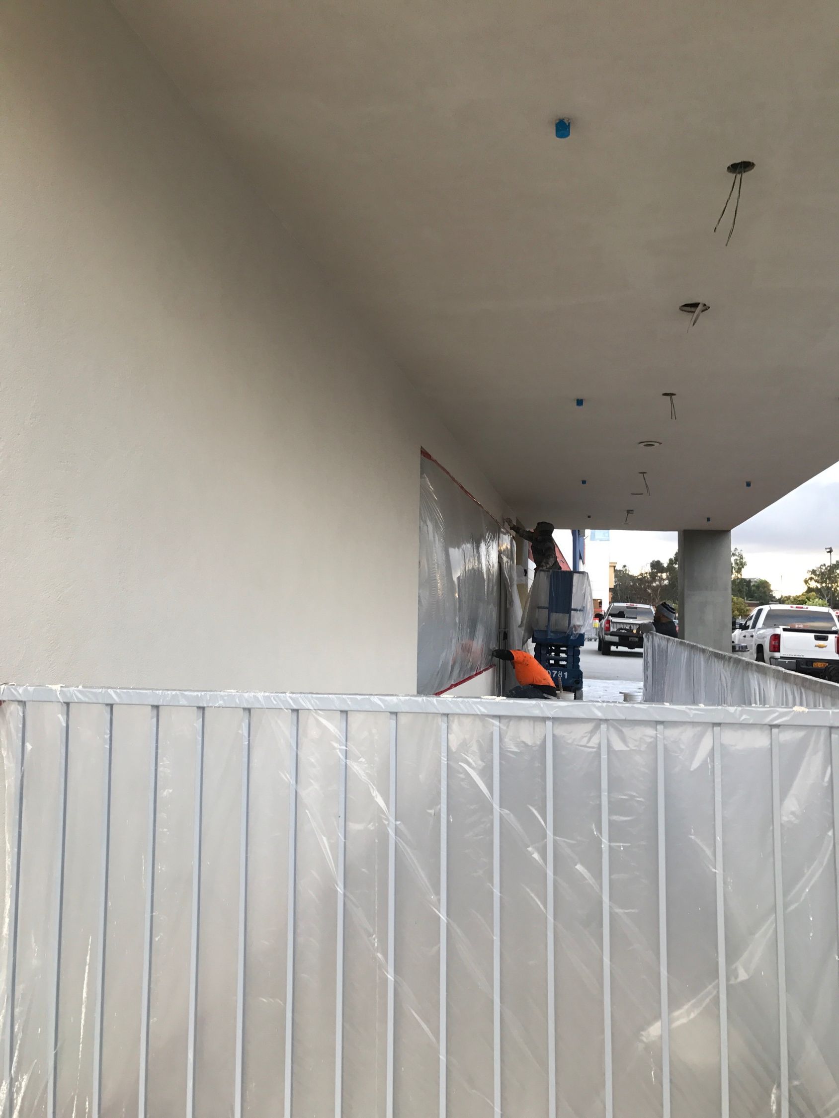 Construction site with a person on a lift, protective barrier, and building exterior.