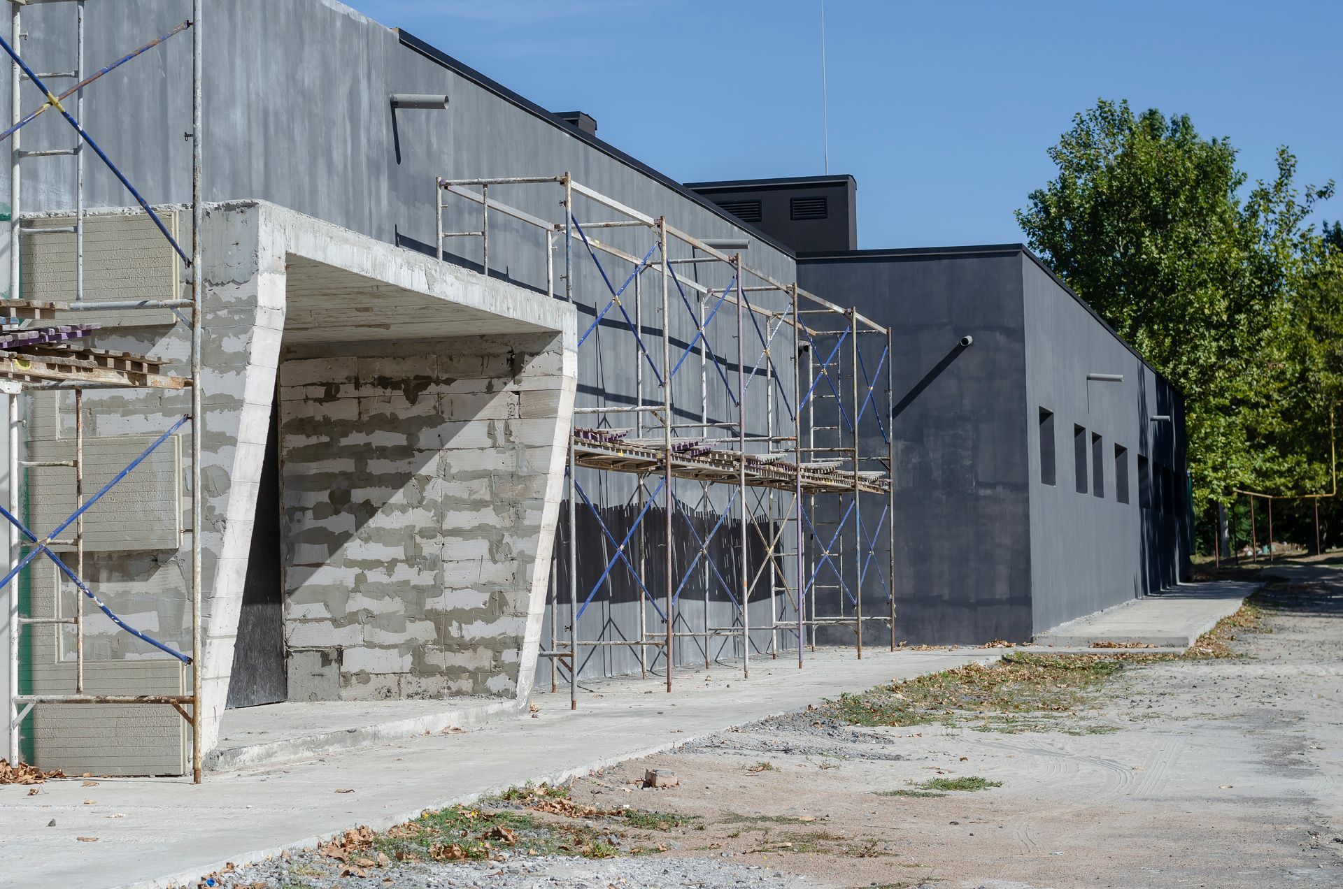 Building under construction with concrete walls, scaffolding, and a clear sky.