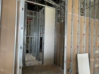 Interior construction with metal studs, drywall, and partially built walls.