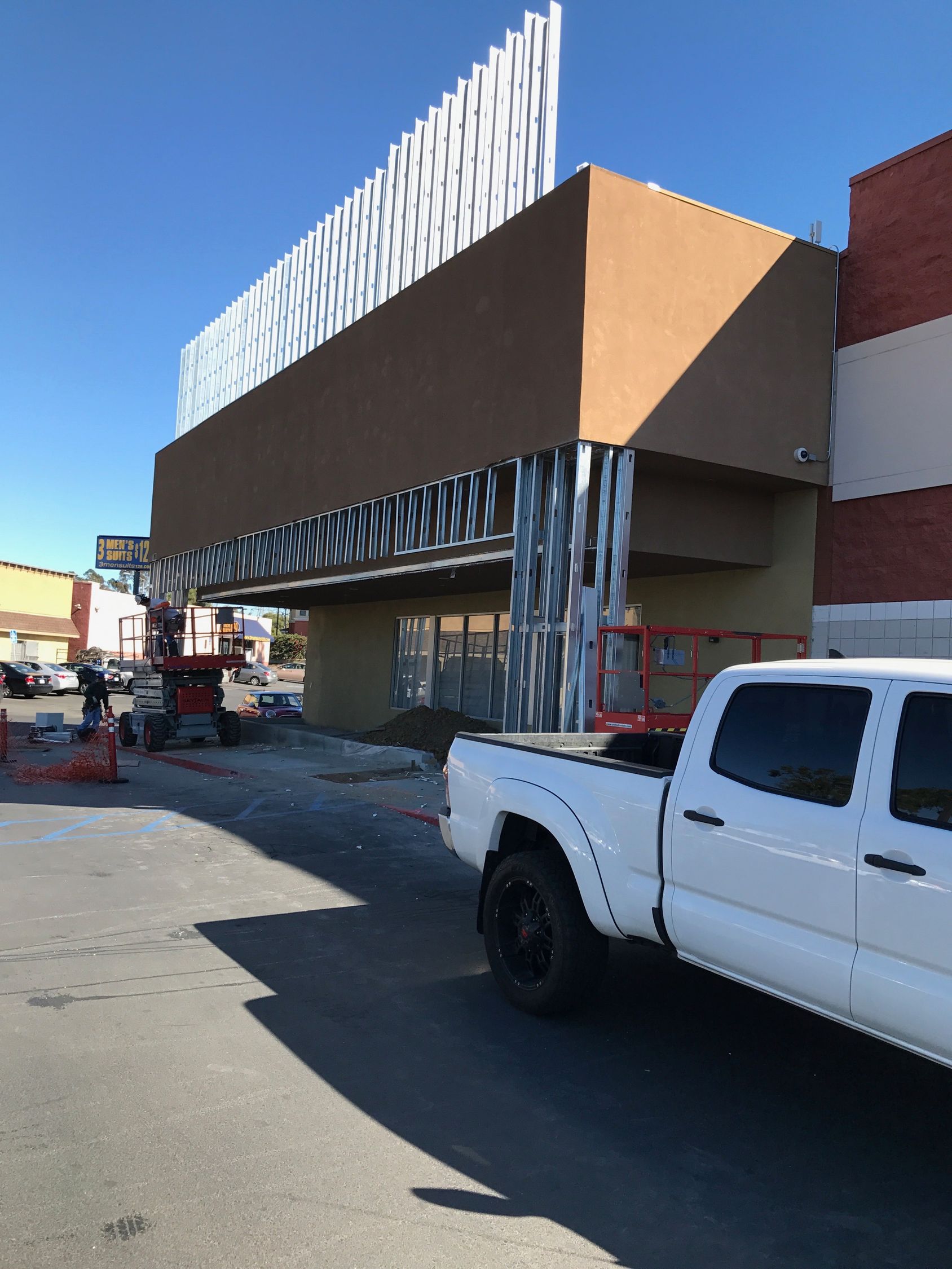 Exterior of a building under construction, with a white truck parked in front.