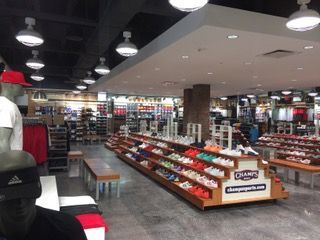 Inside Champs Sports store, shoes displayed on shelves, mannequins wearing clothes, overhead lighting.