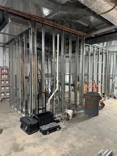Metal framing for a room under construction, with pipes, conduits, and equipment visible.
