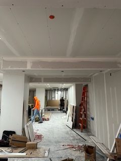 Construction site interior, drywall installation. Workers, tools, unfinished walls and ceiling.