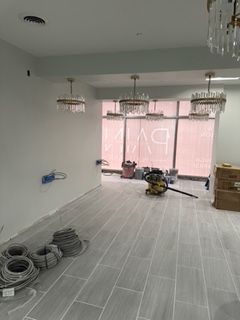 Empty room with gray tiled floor, wires, and crystal chandeliers under construction.