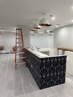 Bar under construction with black and white patterned tile, light fixtures, and a ladder.