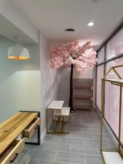 Retail interior: Pink faux tree, shelves, display tables, wood desk, and light fixtures.