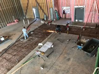 Construction site: Workers cutting metal, installing rebar, and preparing for concrete.