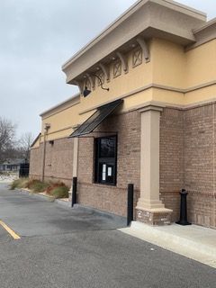 Drive-thru window of a tan and brick building under a cloudy sky.