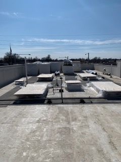 Flat commercial rooftop with HVAC units and various equipment under a clear sky.