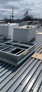 Construction materials on a corrugated metal roof, with an American flag waving in the distance.