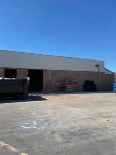 Exterior view of a commercial building with brick walls, tan trim, and a clear blue sky.