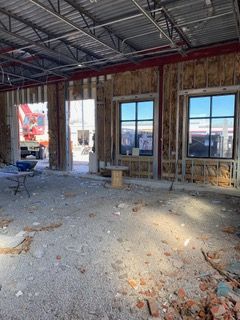 Interior construction site with exposed framing, windows, and debris.