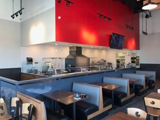 Restaurant interior with red accent wall, booths, and kitchen counter.