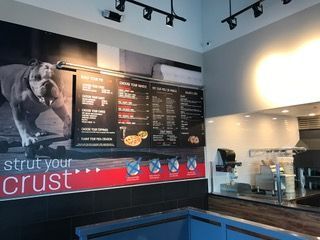 Menu boards in a restaurant with a bulldog mural. Red and black color scheme.
