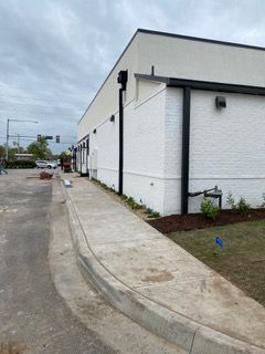 Exterior of a newly constructed white building with a concrete ramp for accessibility. Black trim accents.