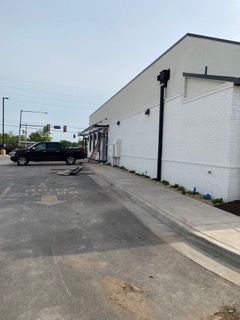 Exterior view of a white brick building with a black truck parked nearby. A ramp leads to the entrance.