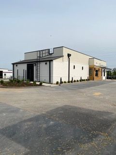 Modern, white commercial building with black trim, and a small parking area in front.