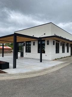 Modern white building with a covered patio, black accents, and large windows.