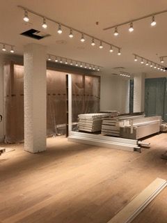 Interior under construction with track lighting, wood floors, and building materials.