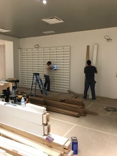 Two workers installing wall paneling in a room under construction.