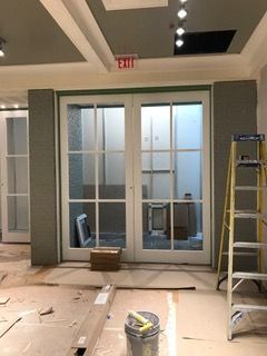 Double white doors with glass panes, exit sign, and construction materials in a room.
