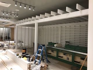 Interior of a building under construction, featuring white wood beams, walls, and shelving.