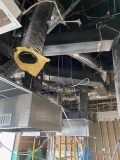 Overhead view of a construction site showing ductwork, metal beams, and unfinished walls with wiring.