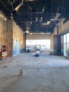 Interior of a building under construction, empty space with exposed ceiling and unfinished walls.