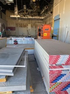 Construction site: drywall, lift, and materials. Ceiling partially open.