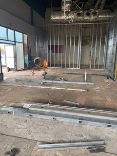 Interior of a commercial space under construction; metal studs frame walls and lie on the concrete floor.