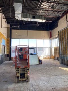 Empty commercial space with construction lift and unfinished walls.