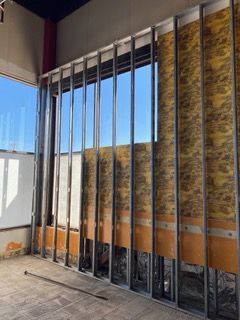 Interior wall construction with metal studs, window, insulation, and exposed elements.