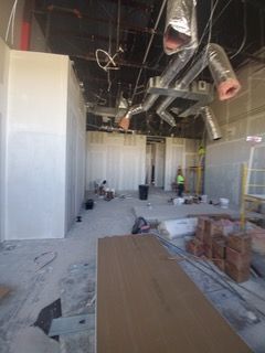 Interior of a room under construction with exposed ductwork, drywall, and construction materials.