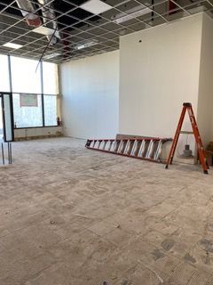 Interior of a room under construction with a long ladder, a step ladder, and white walls.