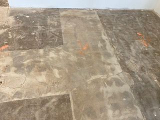 Damaged concrete flooring with visible patches and cracks.