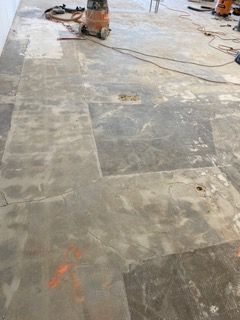 Bare concrete floor with patches, cracks, and vacuum cleaner.