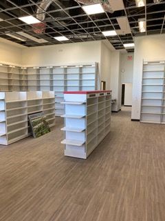 Empty store interior with white shelving and a wooden floor.