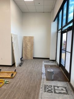 Empty room under construction with new flooring, a wrapped door, and a glass door to the outside.