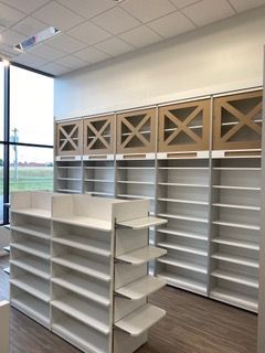 Empty store shelves, white and tan color scheme. Some shelves have X-shaped cabinet doors.
