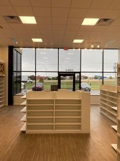 Empty retail space with shelving and large windows looking outside.
