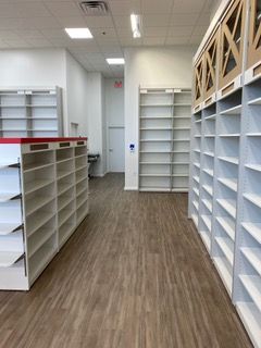 Empty store shelves in a bright room with wood-look flooring.