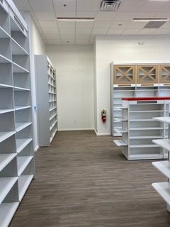 Empty store interior with white shelving and a brown floor.