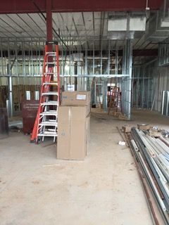 Construction site interior with metal framing, boxes, a ladder, and exposed ceiling.