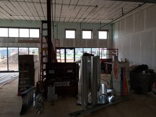 Interior construction site with building materials, windows, and exposed ceiling.