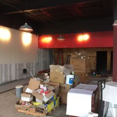 Interior construction site with building materials, red facade, and exposed walls.
